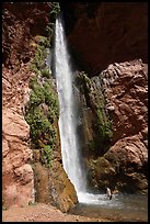 Person standing under the Deer Creek tall desert waterfall in a red rock canyon. Grand Canyon National Park, Arizona ( color)