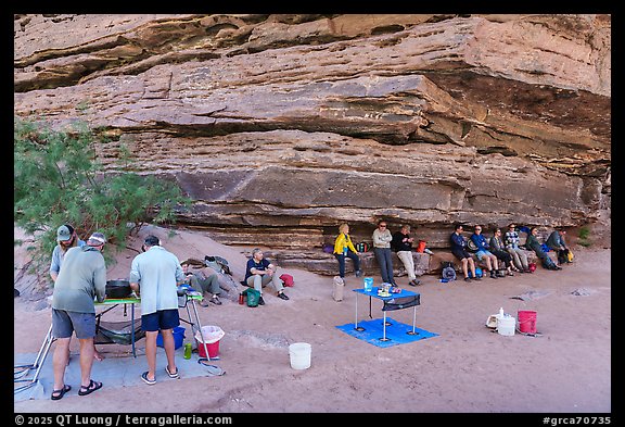 Group of rafters relaxing in the shade of a rock overhang while crew prepares lunch. Grand Canyon National Park, Arizona (color)