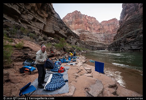 Rafters packing bedding and dry bags on a narrow beach campsite along the Colorado River. Grand Canyon National Park, Arizona (color)