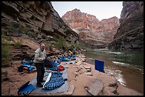 Rafters packing bedding and dry bags on a narrow beach campsite along the Colorado River. Grand Canyon National Park, Arizona ( color)