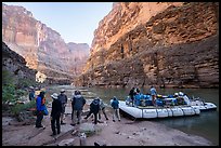 Group of rafters loading gear to a motorized raft at a sandy landing beneath towering Grand Canyon cliffs. Grand Canyon National Park, Arizona ( color)