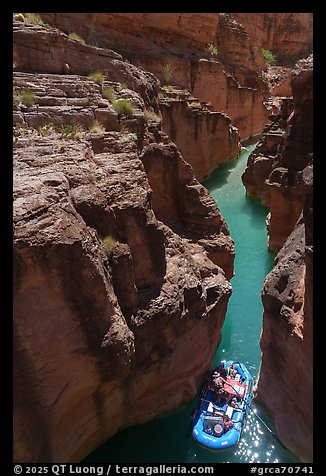 Raft navigating a tight passage through a red rock slot canyon of Havasu Creek with turquoise water. Grand Canyon National Park, Arizona (color)