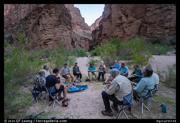 Group of Grand Canyon rafters eating a meal together on folding chairs at the National Canyon campsite. Grand Canyon National Park, Arizona (color)