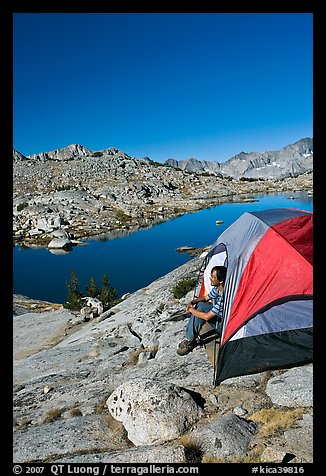 Man looking out from tent above lake, morning, Dusy Basin. Kings Canyon National Park, California