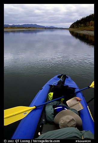 Canoeist reading a book while floating downriver. Kobuk Valley National Park, Alaska (color)