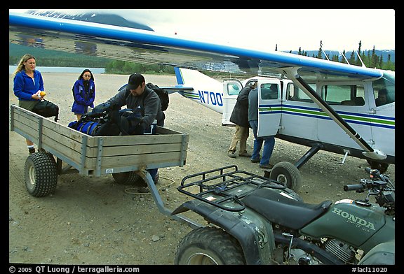 Unloading the gear from the plane to a trailer on the Port Alsworth airstrip. Lake Clark National Park, Alaska (color)