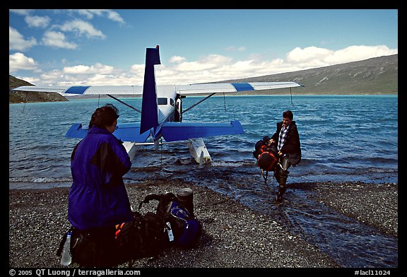 Pilot unloading a backpack from the floatplane on Lake Turquoise. Lake Clark National Park, Alaska