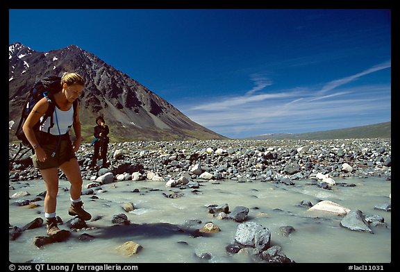 Hiker crossing a stream next to Lake Turquoise. Lake Clark National Park, Alaska