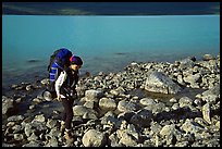 Backpacker walking on rocks on the shore of Turquoise Lake. Lake Clark National Park, Alaska