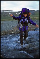 Backpacker balancing herself while crossing a stream. Lake Clark National Park, Alaska ( color)