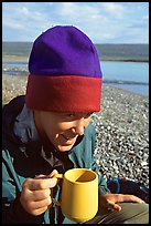 Backpacker drinking from a cup, with mosquitoes on her hat. Lake Clark National Park, Alaska ( color)