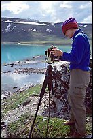 Large format photographer with camera on the shores of Turquoise Lake. Lake Clark National Park, Alaska ( color)