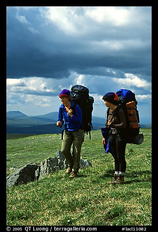 Two women backpackers pausing in the tundra with alpine flowers in the background. Lake Clark National Park, Alaska (color)
