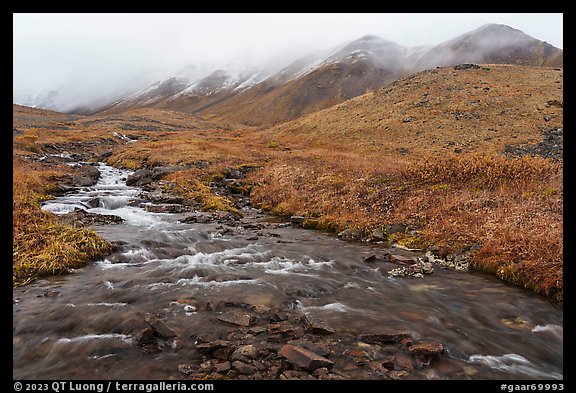 Creek flowing below peaks with fresh snow. Gates of the Arctic National Park, Alaska, USA.