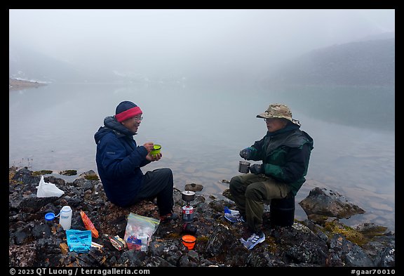 Backpackers eating on shore of foggy lake. Gates of the Arctic National Park, Alaska, USA.