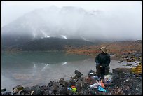Backpacker eating near lake with foggy mountain. Gates of the Arctic National Park ( color)