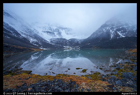 Lake and Three River Mountain emerging from the clouds. Gates of the Arctic National Park, Alaska, USA.