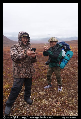 Nunamiut man and visiting backpacker with cell phones. Gates of the Arctic National Park, Alaska, USA.