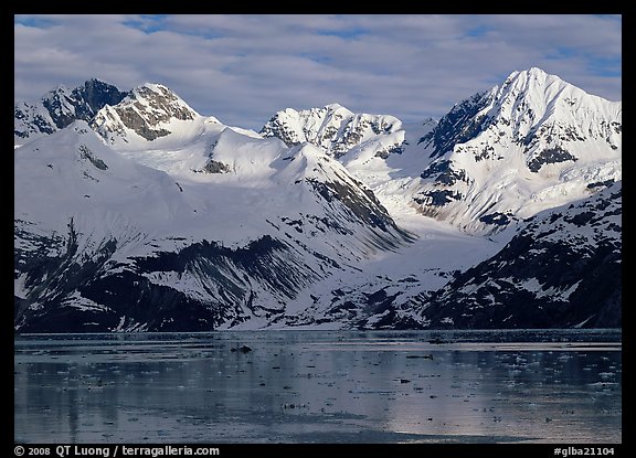 Coastal mountains with glacier dropping into icy fjord. Glacier Bay National Park, Alaska, USA.