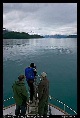 Film crew working on the bow of a small boat. Glacier Bay National Park, Alaska, USA.
