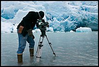 Cameraman standing in water at the base of Reid Glacier. Glacier Bay National Park, Alaska, USA. (color)