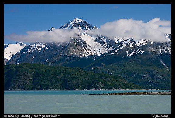 Snowy peaks and clouds raising above turquoise waters in sunny weather. Glacier Bay National Park, Alaska, USA.