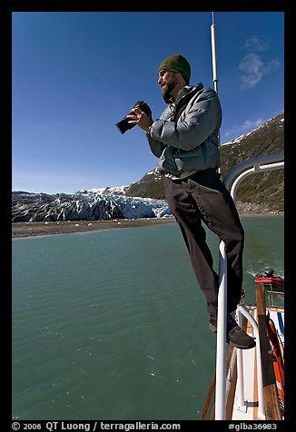 Photographer perched on boat in Reid Inlet. Glacier Bay National Park, Alaska, USA.