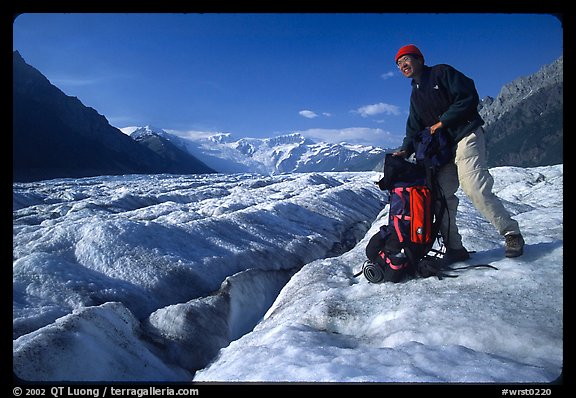 Hiker reaching into backpack on Root glacier. Wrangell-St Elias National Park, Alaska, USA.