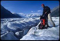 Hiker reaching into backpack on Root glacier. Wrangell-St Elias National Park ( color)
