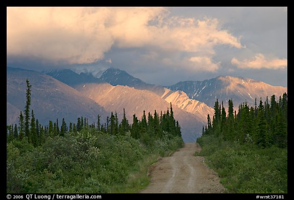 Gravel road leading to mountains lit by sunset light. Wrangell-St Elias National Park, Alaska, USA.
