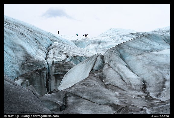 Distant hikers on Root Glacier from below. Wrangell-St Elias National Park, Alaska, USA.