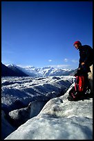 Hiker reaches for item in backpack on Root Glacier. Wrangell-St Elias National Park ( color)