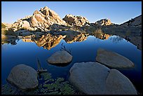 Rockpiles reflected in pond, Barker Dam, sunrise. Joshua Tree National Park, California, USA.