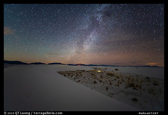Backcountry camping area with lit tent at night. White Sands National Park, New Mexico, USA.