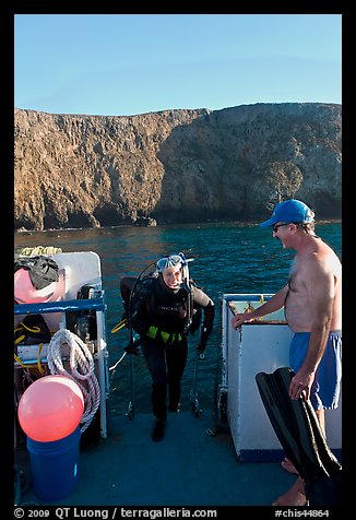 Woman diver stepping onto boat and Annacapa Island. Channel Islands National Park (color)