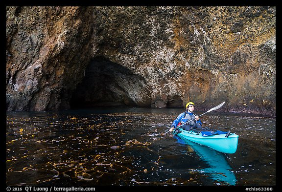 Kayaker paddling out of sea cave, Santa Cruz Island. Channel Islands National Park (color)