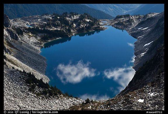 Fluffy clouds reflected in blue lake, North Cascades National Park.  (color)