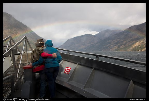 Couple at bow of boat looking at rainbow over Lake Chelan, North Cascades National Park Service Complex. Washington, USA.