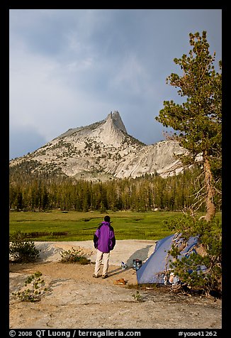 Camper standing next to tent looks at Cathedral Peak, evening. Yosemite National Park, California, USA.
