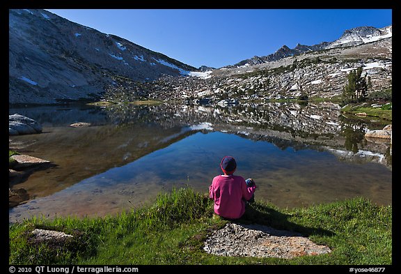 Hiker sitting by alpine lake, Vogelsang. Yosemite National Park, California, USA.