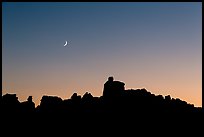 Crescent moon at sunset and Doll House spires. Canyonlands National Park, Utah, USA.