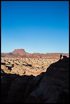 Hiker standing in silhouette above the Maze. Canyonlands National Park, Utah, USA. (color)