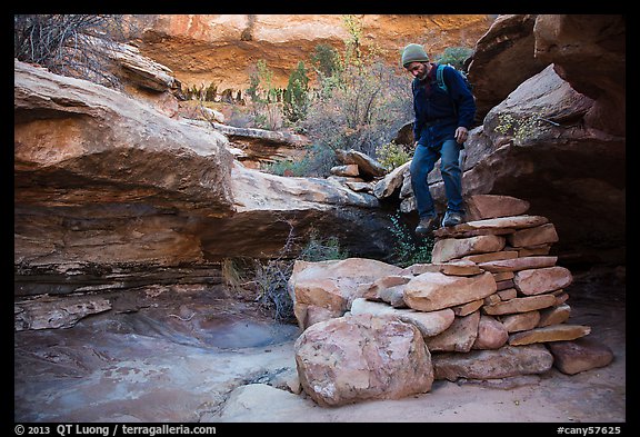 Hiker stepping down on primitive stairs, Maze District. Canyonlands National Park, Utah, USA.