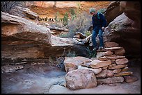 Hiker stepping down on primitive stairs, Maze District. Canyonlands National Park, Utah, USA. (color)