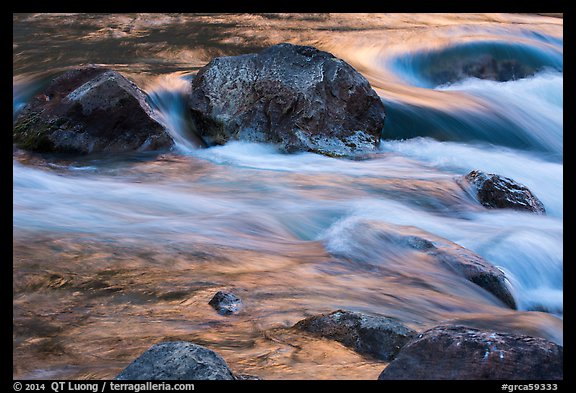 Boulders and rapids with glow from canyon walls reflected. Grand Canyon National Park, Arizona, USA.