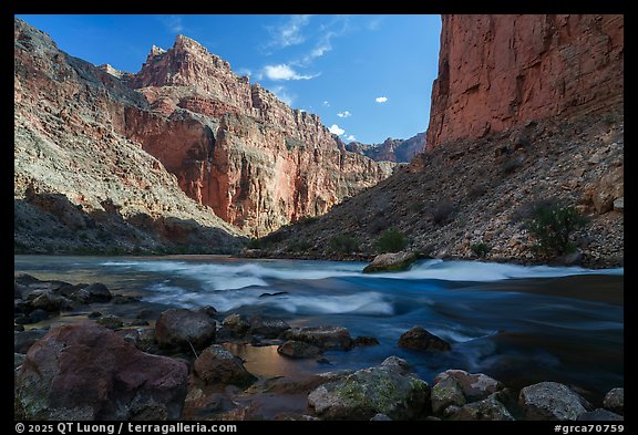 President Harding rapid rushes past weathered boulders under towering red rock cliffs lit by afternoon sun. Grand Canyon National Park (color)