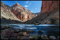President Harding rapid rushes past weathered boulders under towering red rock cliffs lit by afternoon sun. Grand Canyon National Park ( color)