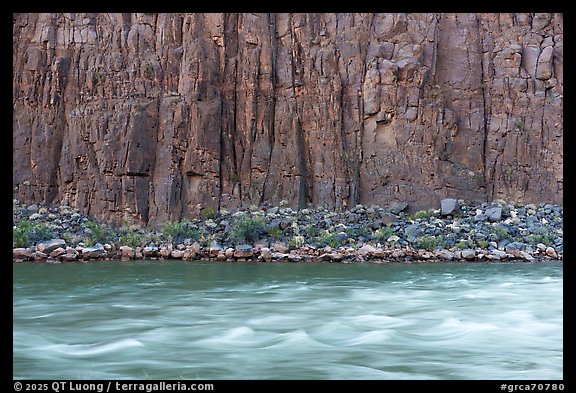 Dark basalt cliffs rise vertically from the river, their base lined with talus and scattered desert vegetation. Grand Canyon National Park (color)