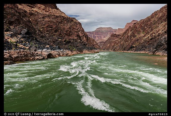 Whitewater churns through rapids framed by volcanic black schist and pastel cliffs. Grand Canyon National Park (color)
