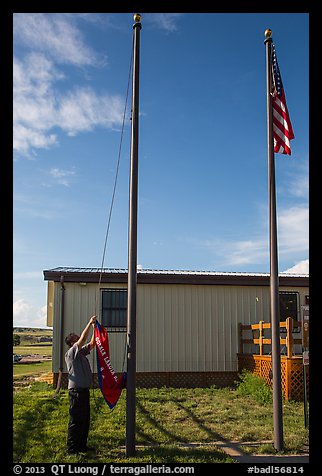 Ranger lowering Ogala Lakota flag, White River Visitor Center. Badlands National Park, South Dakota, USA.